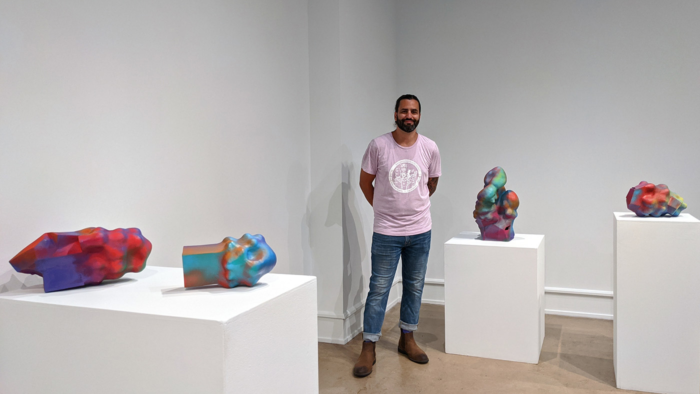 Chuck Purviance stands near four of his brightly colored sculptures.