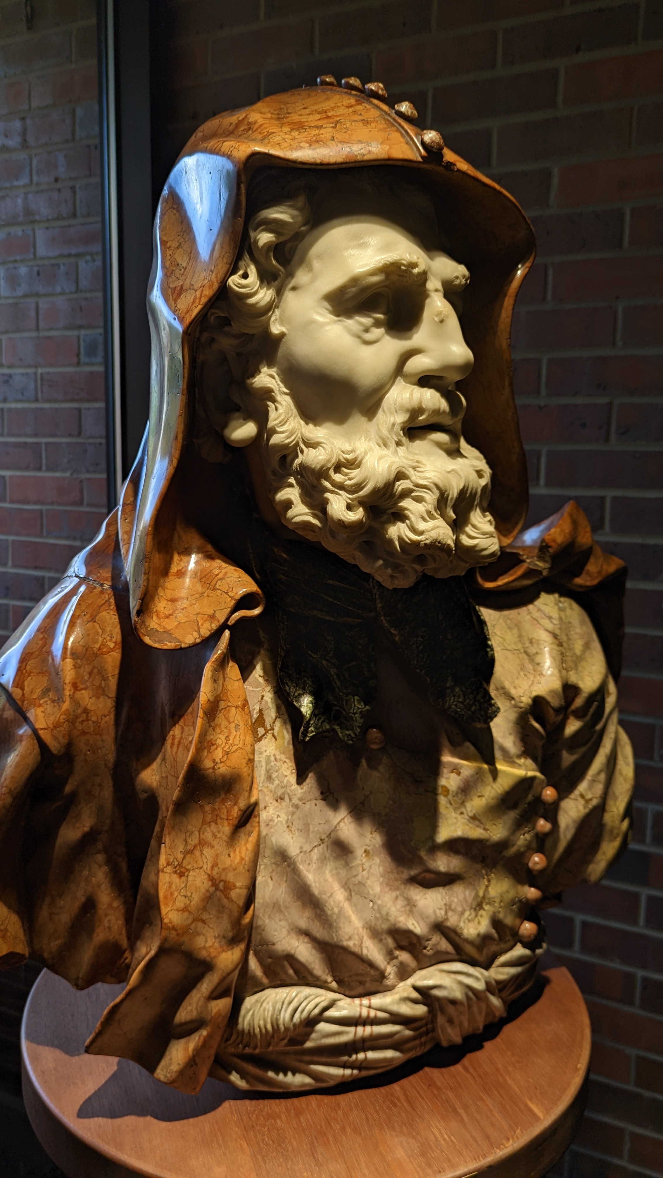 A portrait of the Rigoletto statue, close up. Showcases the details of the statue's face a hood with strong shadows accenting the photo