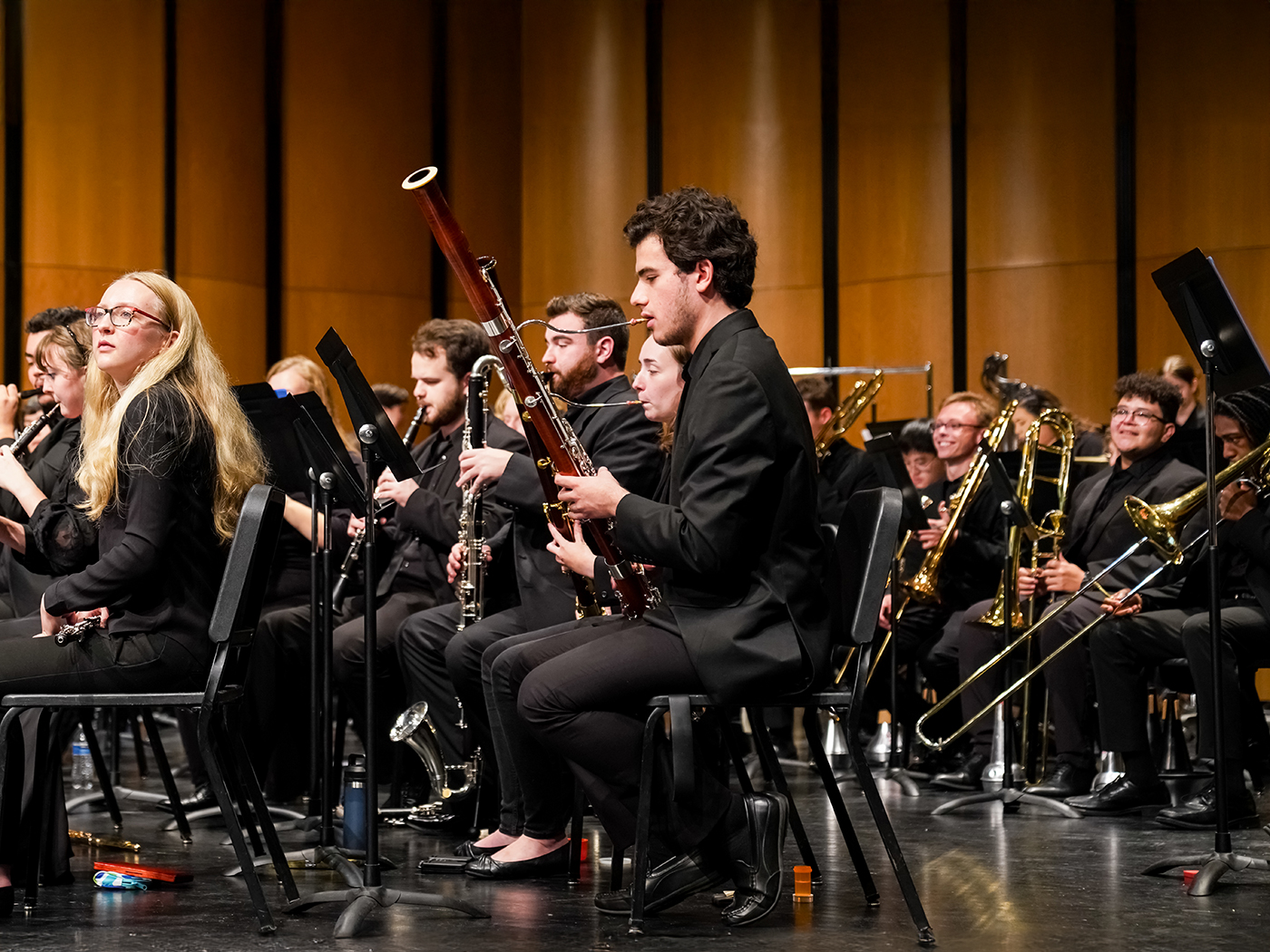 WSU band students in the woodwinds and brass section seated on stage in concert