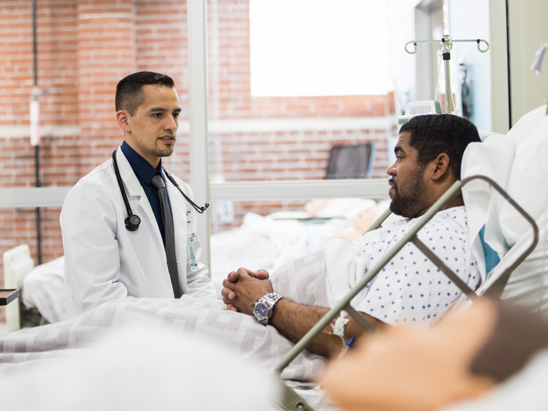 Physician Associate talking with a patient in a hospital bed Physician Associate talking with a patient in a hospital bed