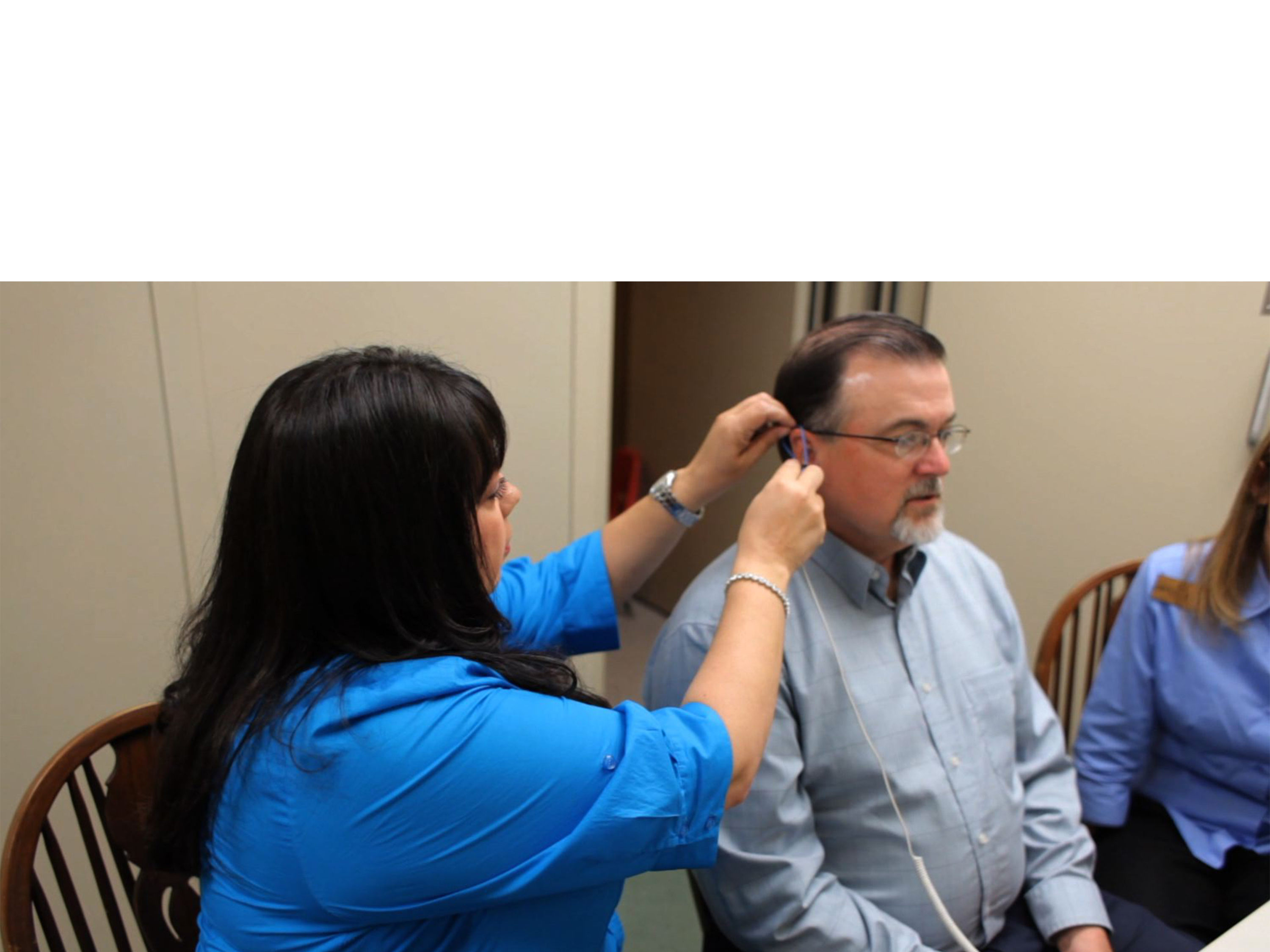 audiologist fits patient with hearing aid