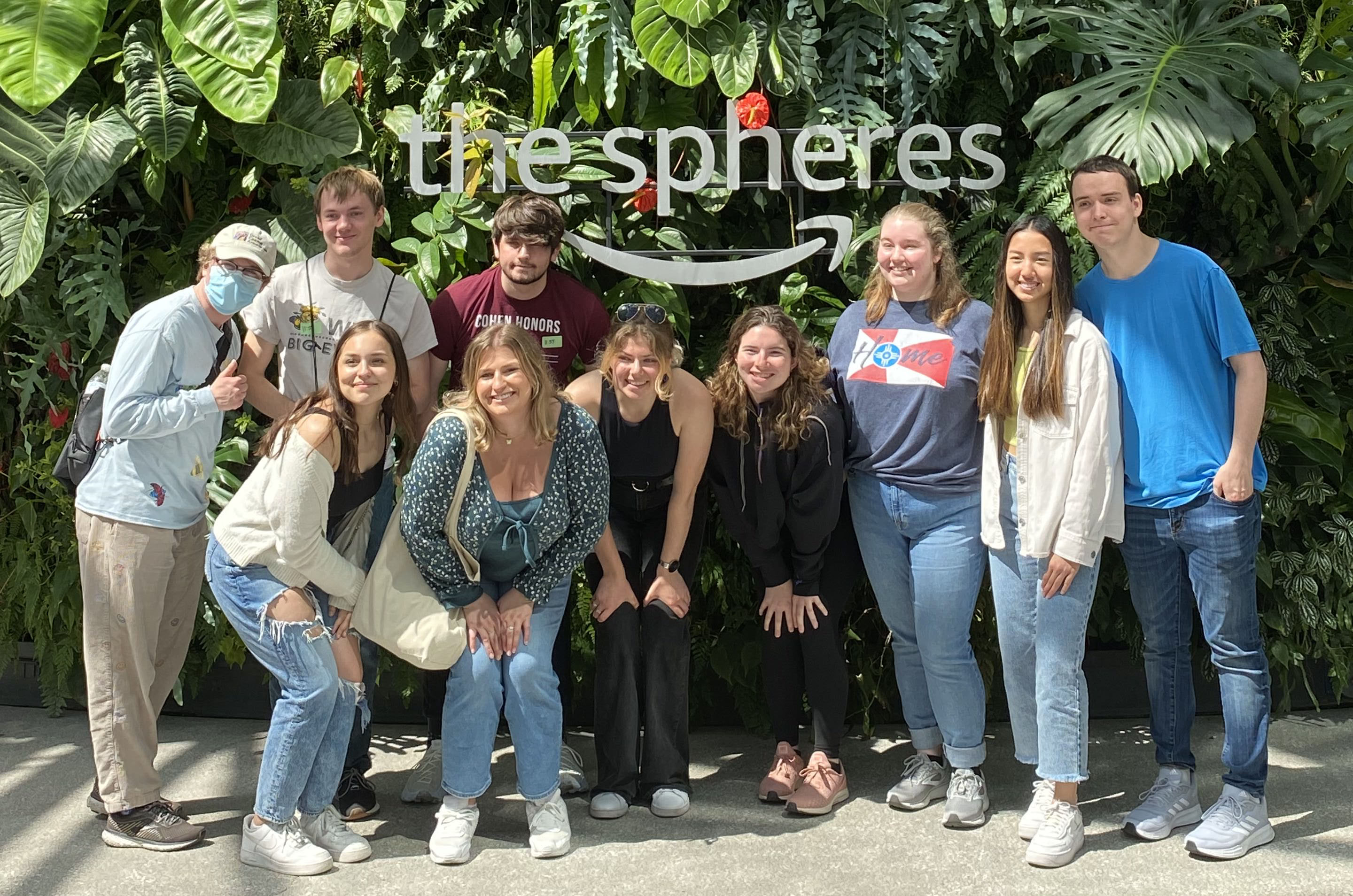 The 2022 Lead for Tomorrow Leadership Academy students posing for a picture at Amazon's The Spheres facility. There are 10 individuals in the photo, posing in front of a sign reading "the spheres" with the Amazon logo beneath and a plant-filled background.