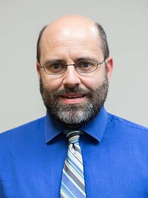 Headshot photo of Dr. Neal Allen in a bright white button-down shirt and blue/gray striped tie.