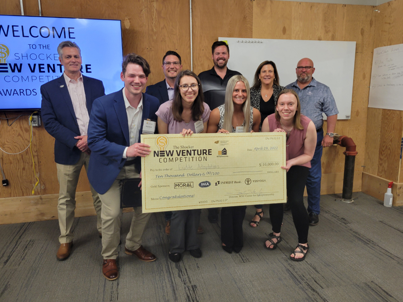 The team members of eurdite hold the giant check as they pose with the finals judges.