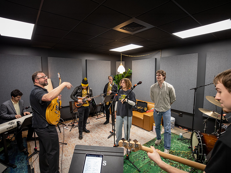 Students practicing in a recording studio with a faculty member.