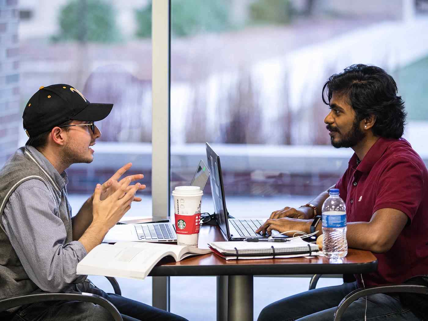 Two students discuss an assignment over coffee at the Rhatigan Student Center