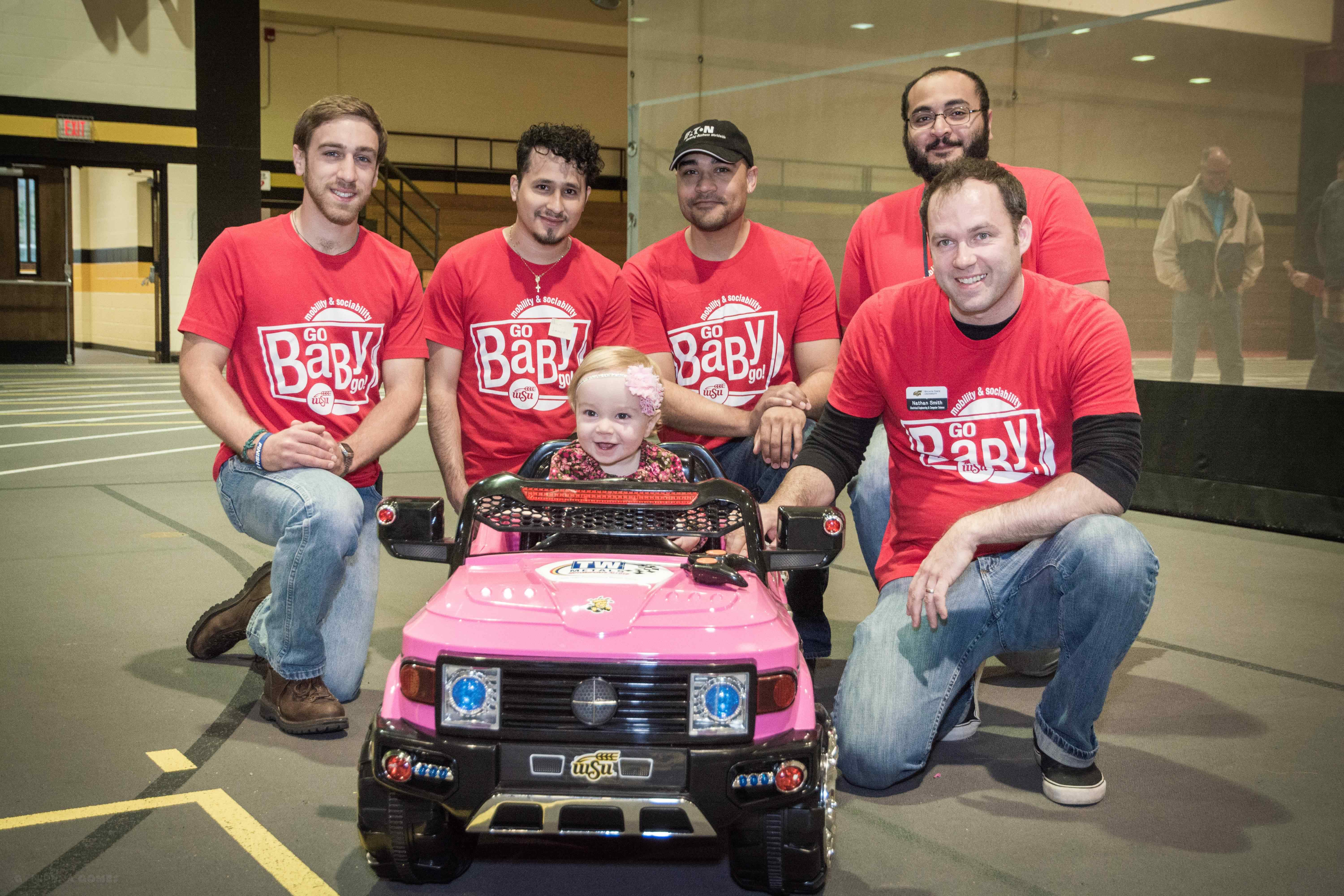 Engineering students pose in front of electric car for Go Baby Go.