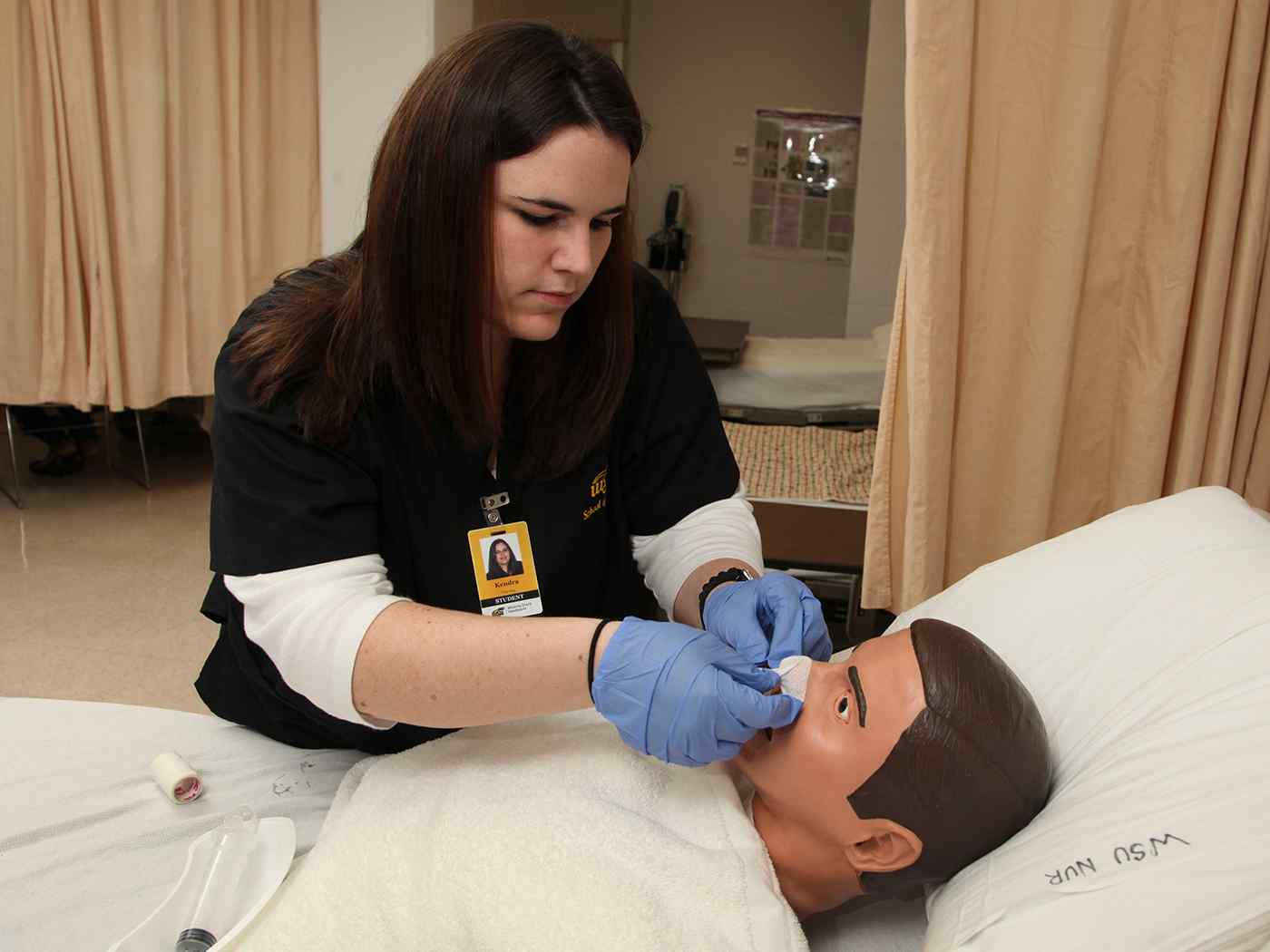 A nursing student works with a health mannequin