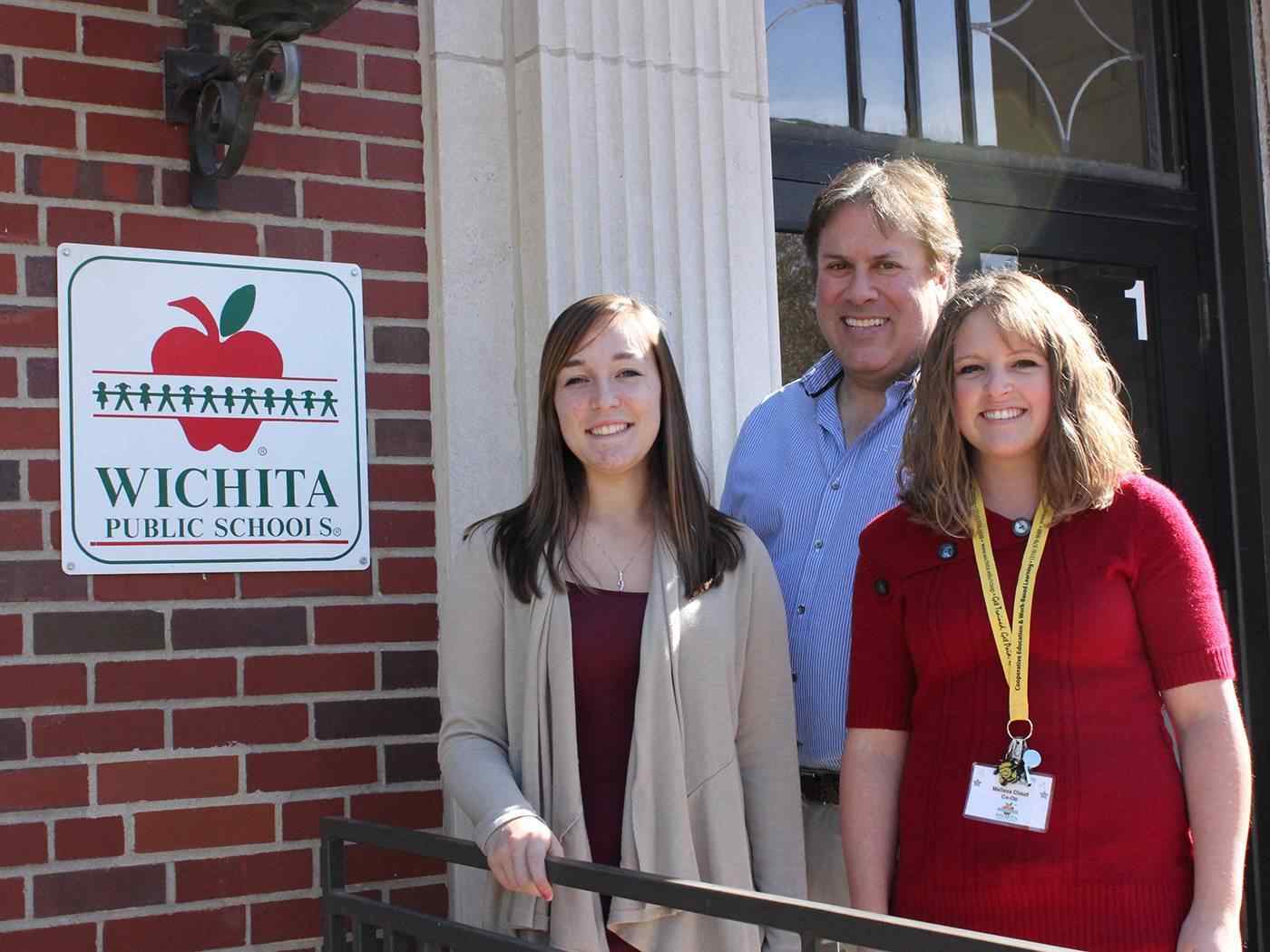 Three teacher education majors pose in front of a Wichita Public Schools building