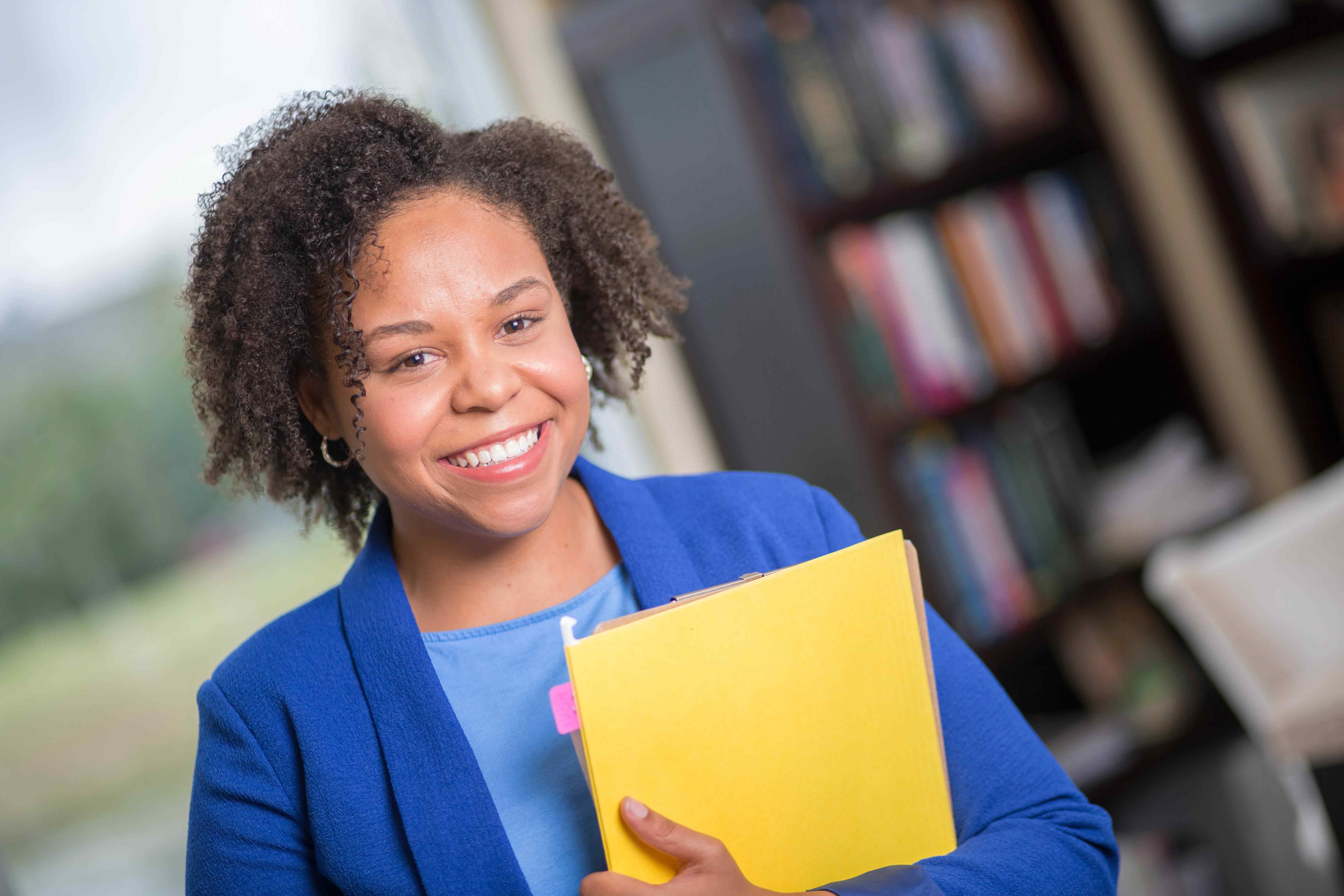 Business student smiling and holding a folio