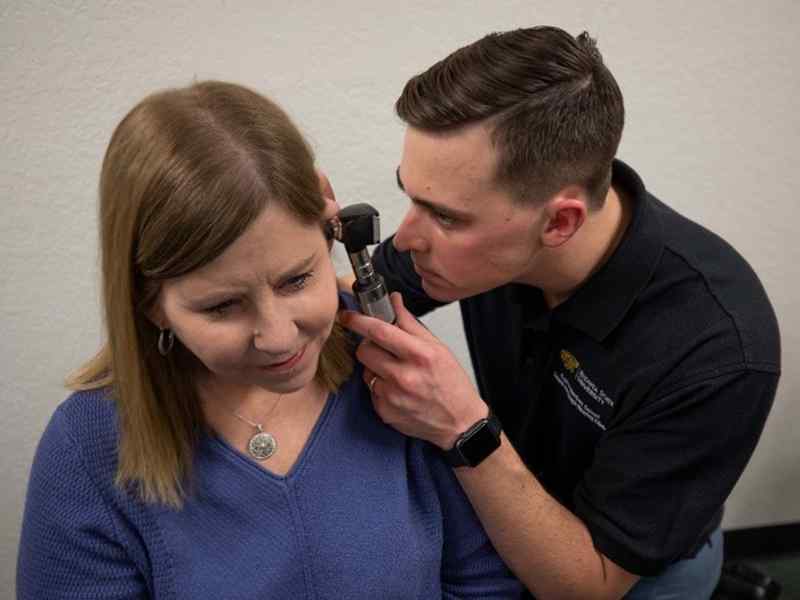 A student examines a patient's ear
