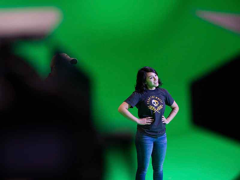 A student acts in front of a green screen