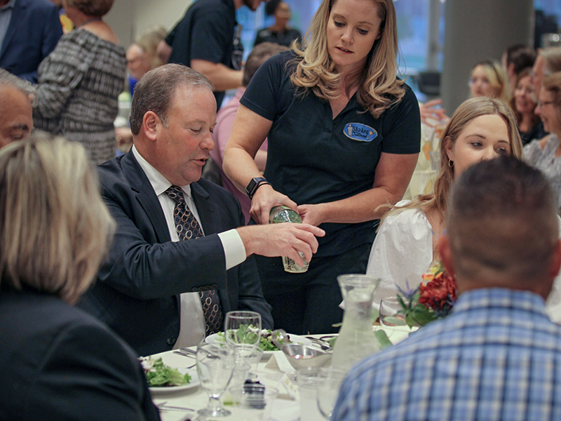 A hospitality employee helps guests at a dining event.