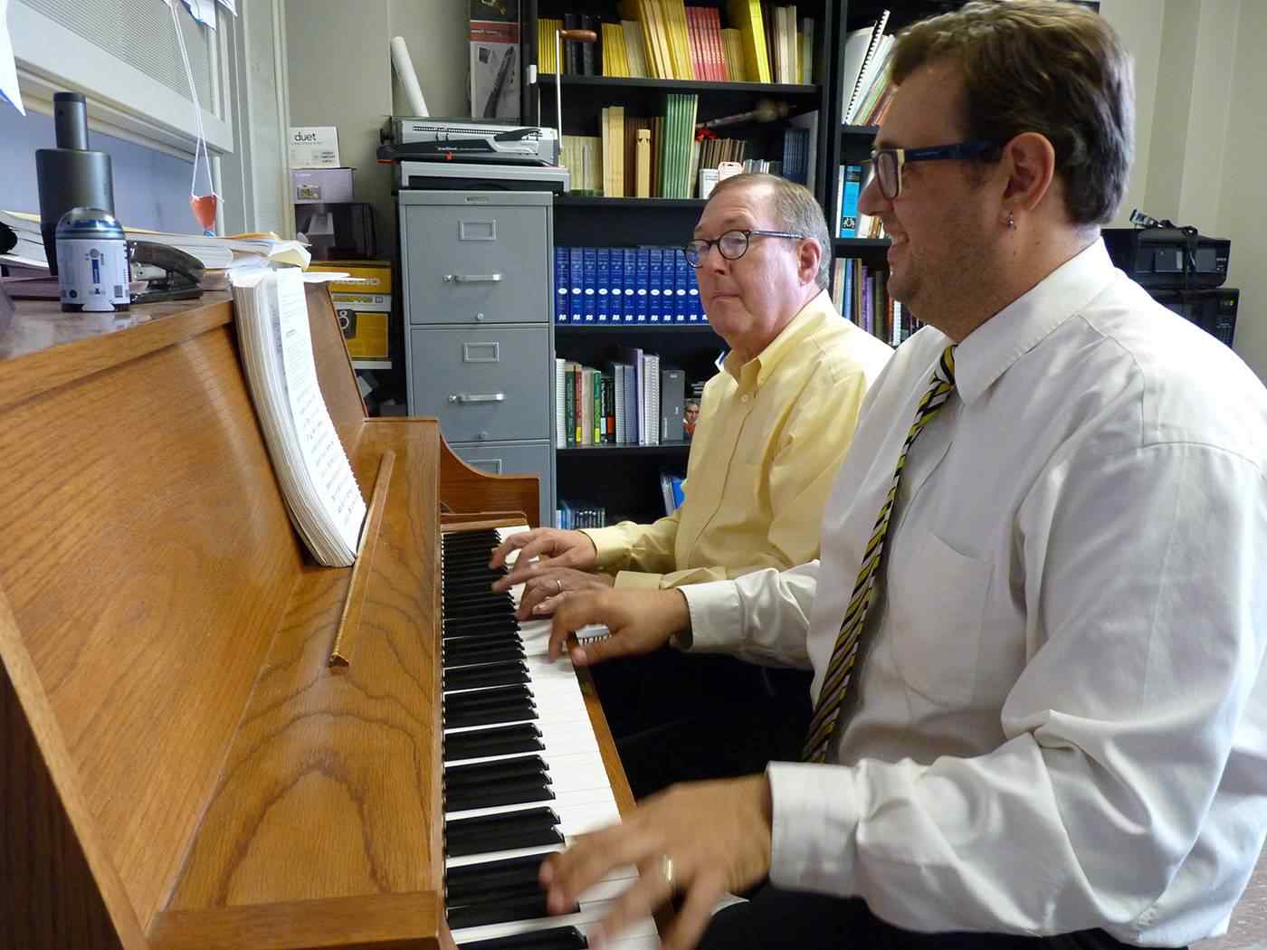 Professor teaching a student on the piano.