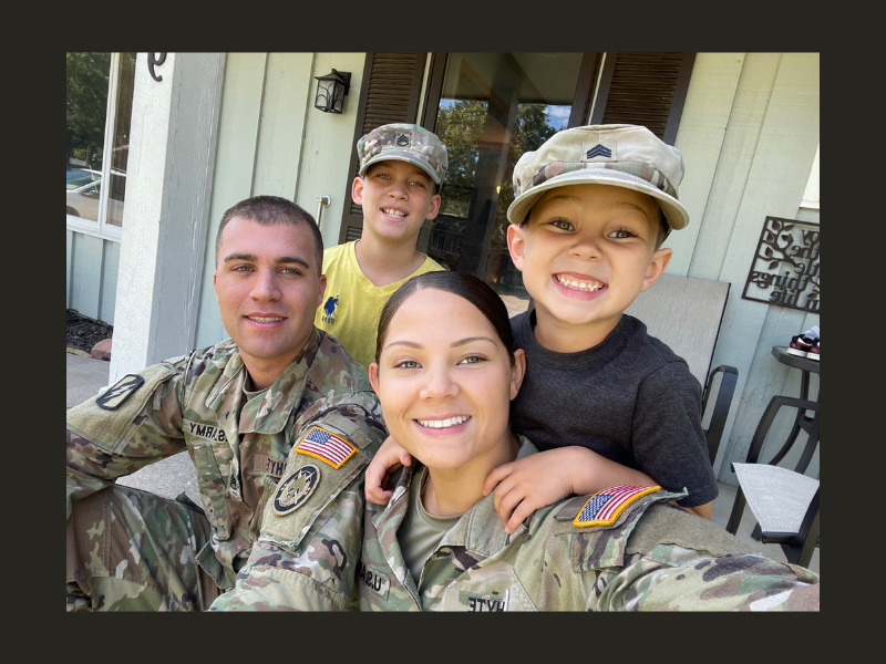 WSU Shocker student stands proudly in a service member uniform, posing with her family beside her, all smiling together for the photo.