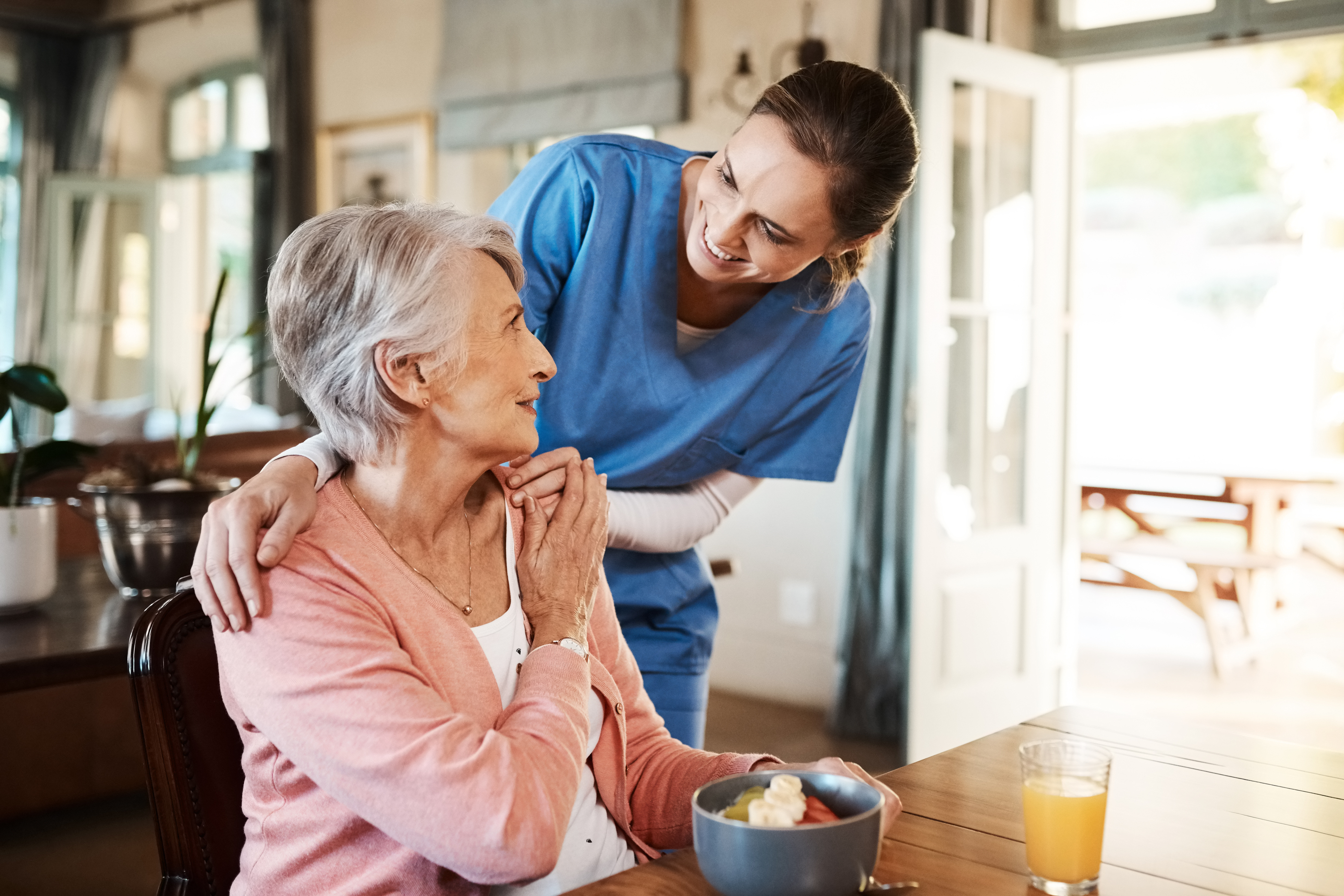 Caregiver smiling at older adult at breakfast table