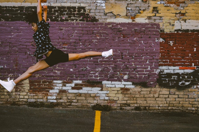 Person leaping in front of brick wall.