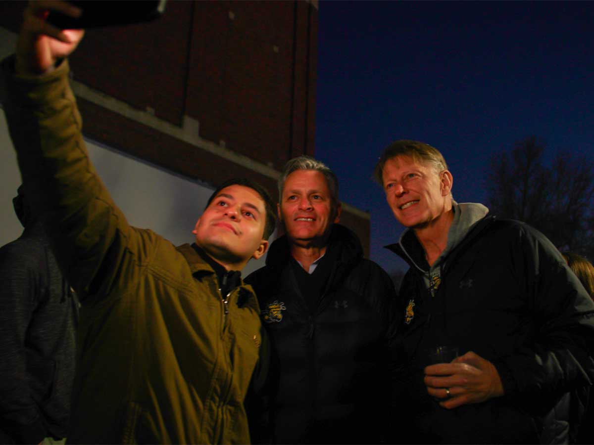 Rick Muma and Rick Case pose for a selfie with a student