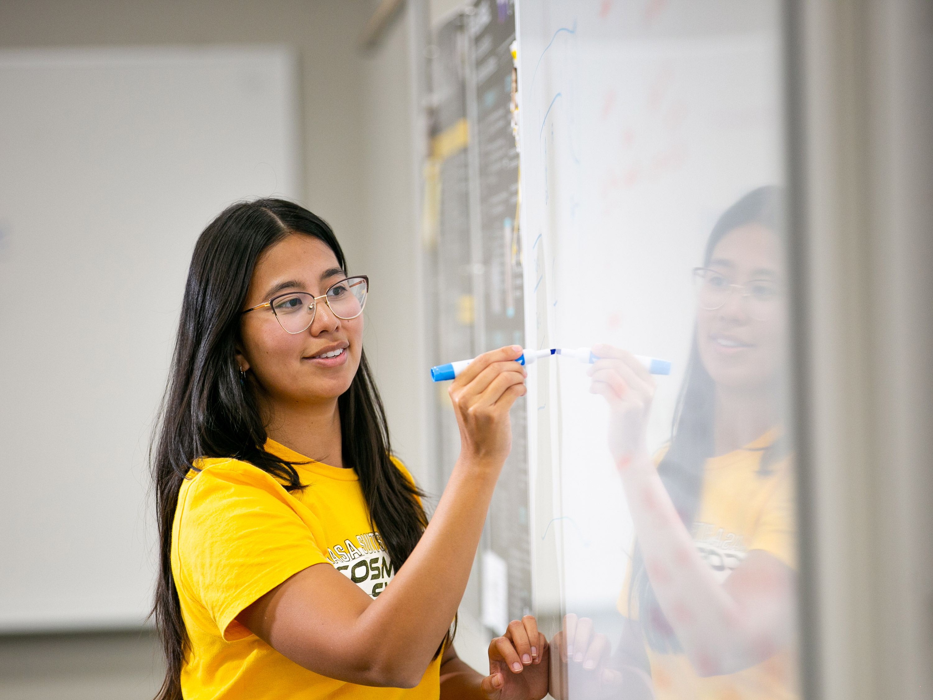 A graduate student writes on a whiteboard.
