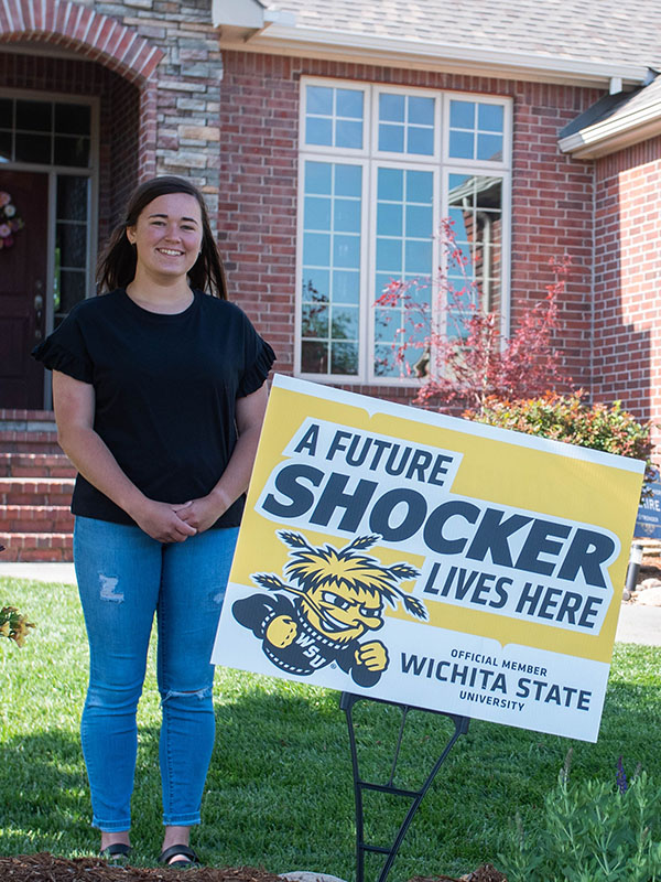 A female student poses with her future shocker yard sign