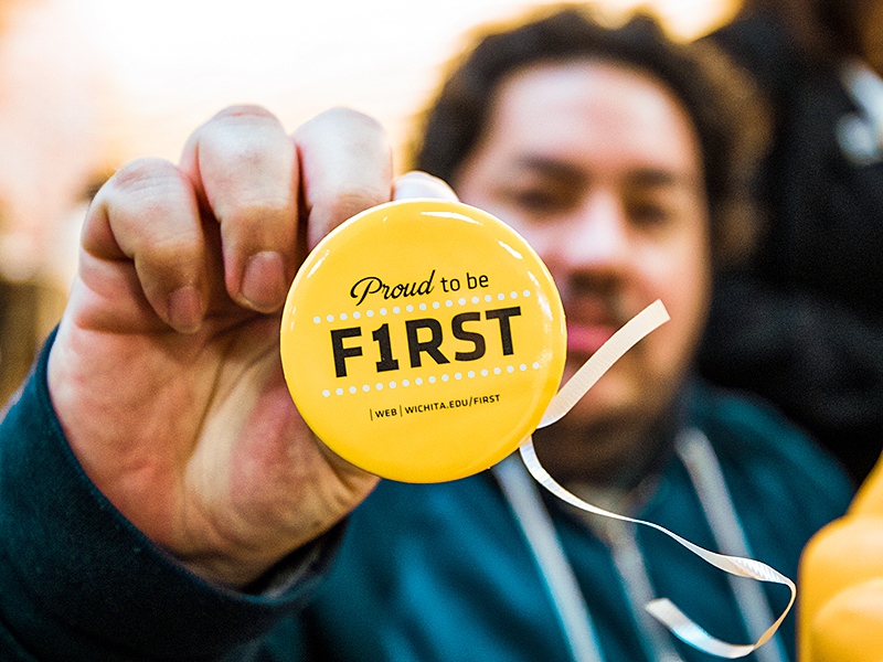A student holds up a First Gen student button.