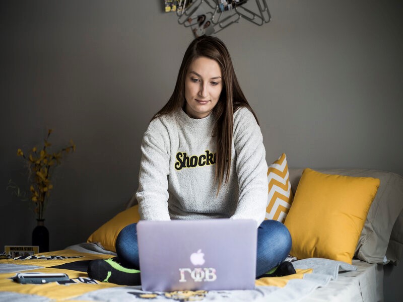 Student sitting on bed on laptop