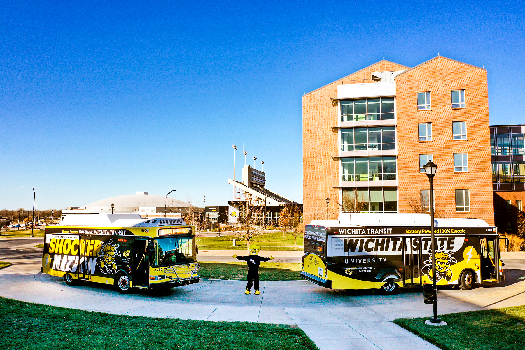 Wu posing with Wichita State Shuttle Busses.