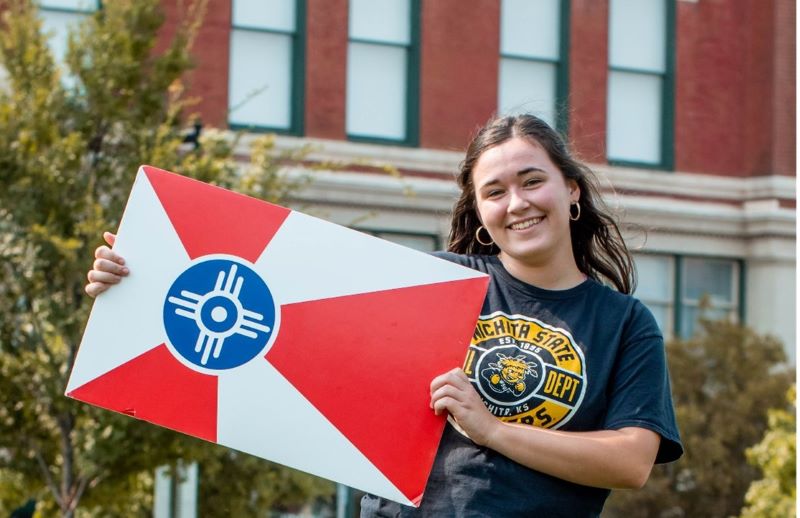 Claire holding the city of Wichita flag on campus at Wichita State
