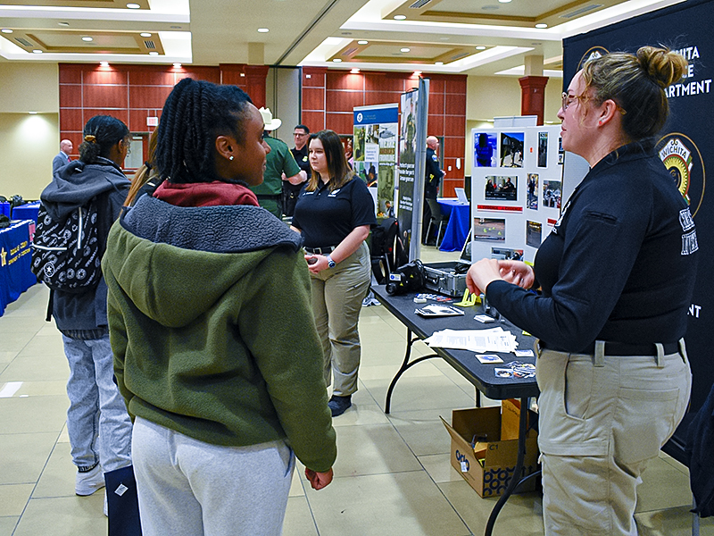 Students chat with members of the Wichita Police Department during the career fair sponsored by the School of Criminal Justice.