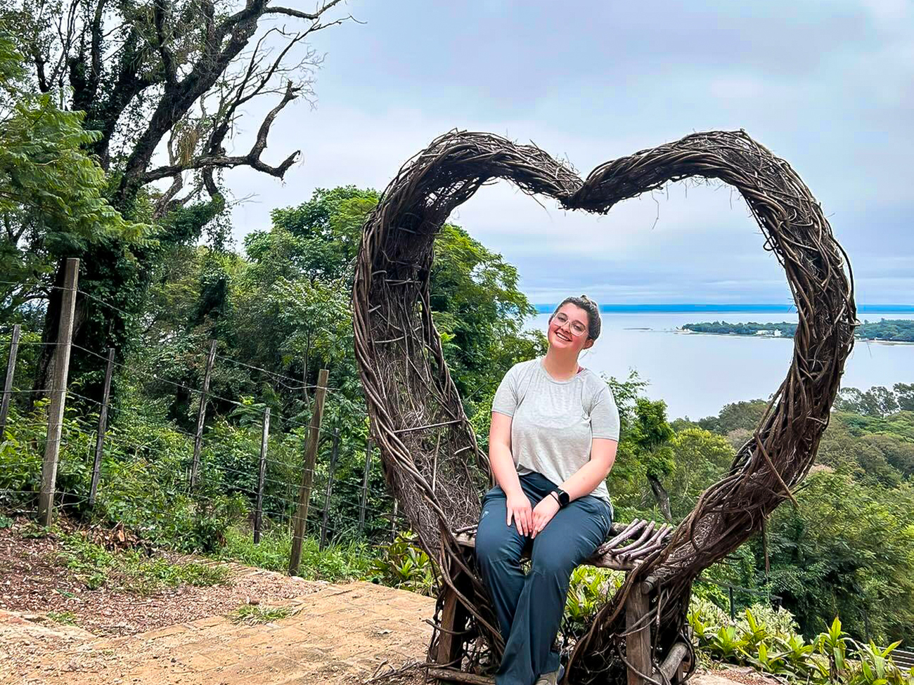 Tyllor Childers posing for a photo underneath an arch near a lake in Paraguay.