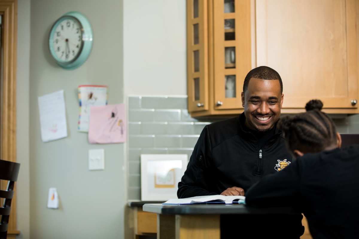 Student is studying at the countertop in a home across from a child who is also working at the counter.