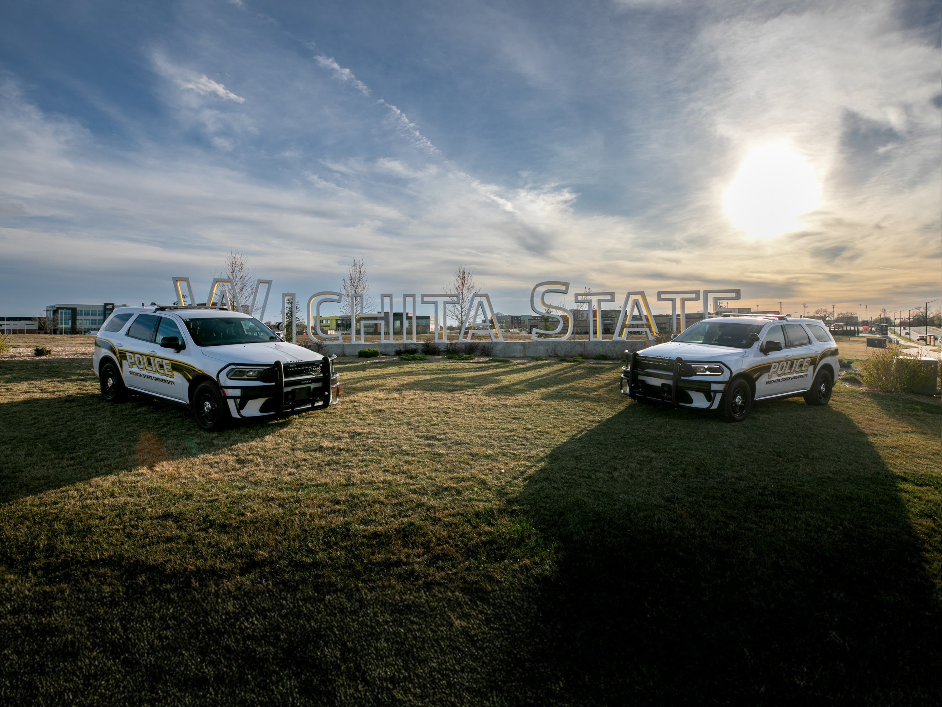 Two Wichita State University Police vehicles parked on opposite sides of a "Wichita State" sign.