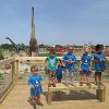 A group of children stand in front of a dinosaur park.