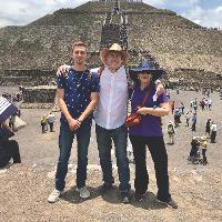 Three people standing with the Teotihuacan pyramid in the background.