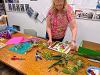 An instructor assembling a collage of various flora on a wooden table.