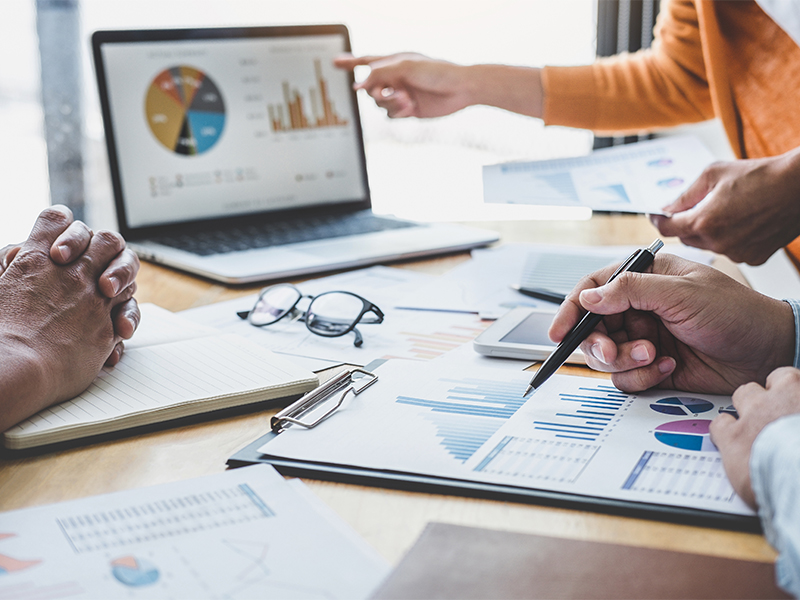 A photo of people looking at and handling papers with charts and graphs