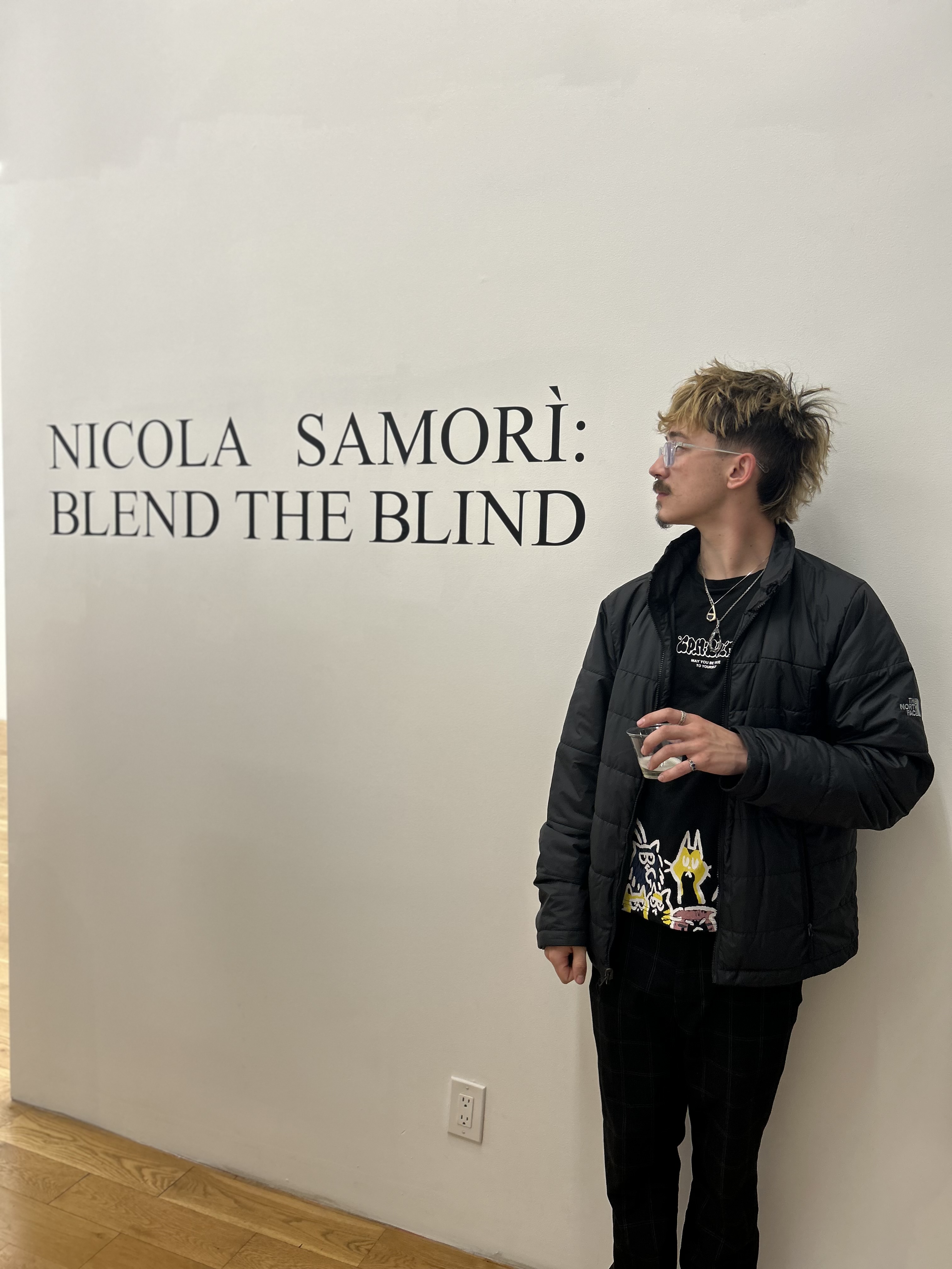 Photo of Mason Snyder in front of a wall with the phrase "nicola samori: blend the blind" written on it."