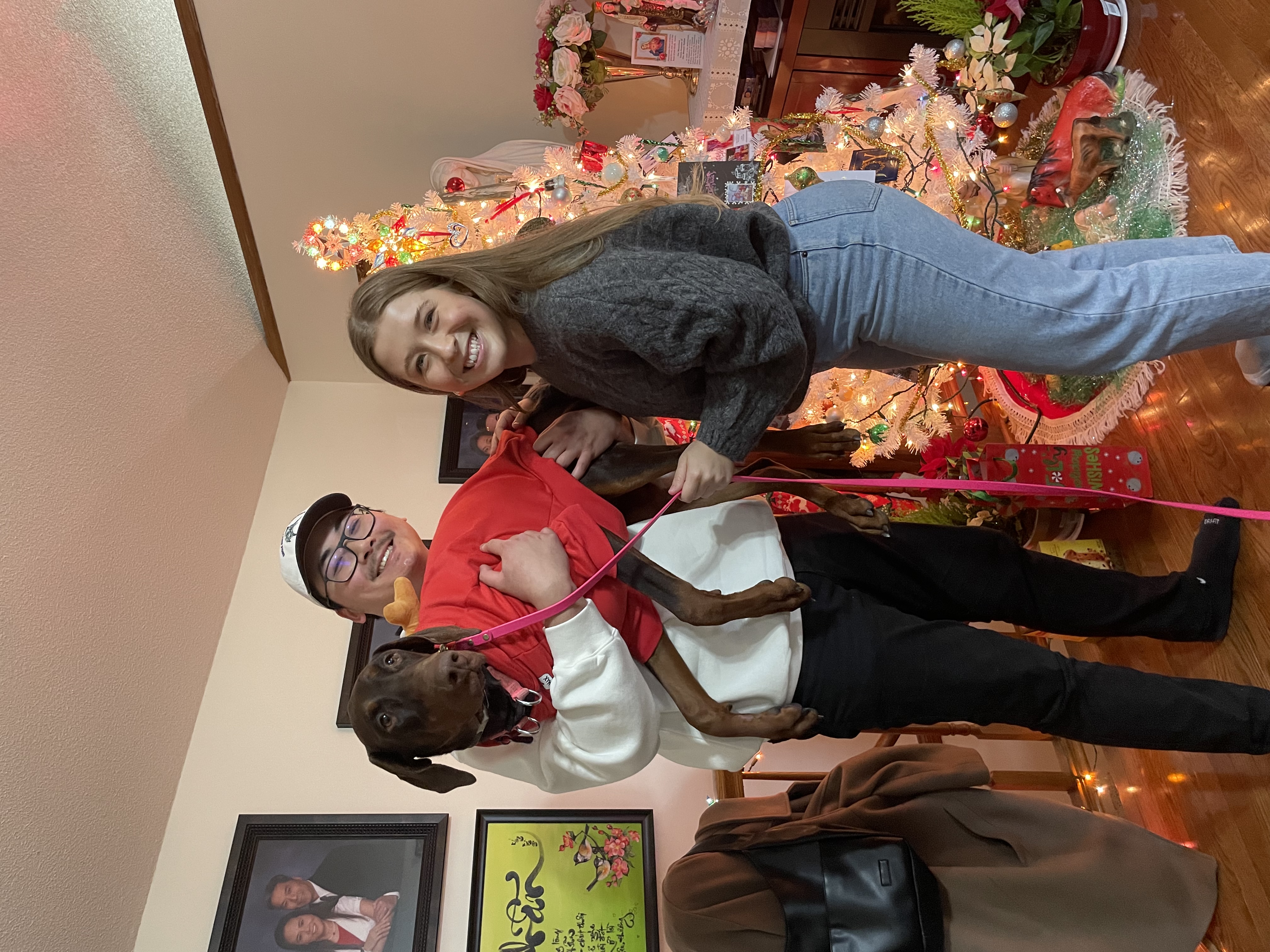 Photo of Peter Vu and one other. Peter is holding a dog that is wearing a red sweater