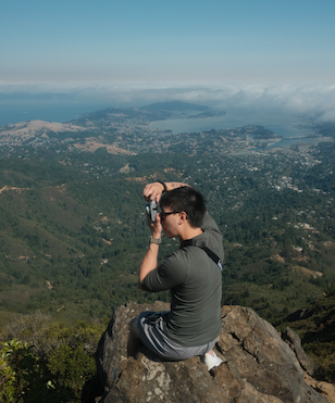 Kevin Le taking a photo on top of a mountain