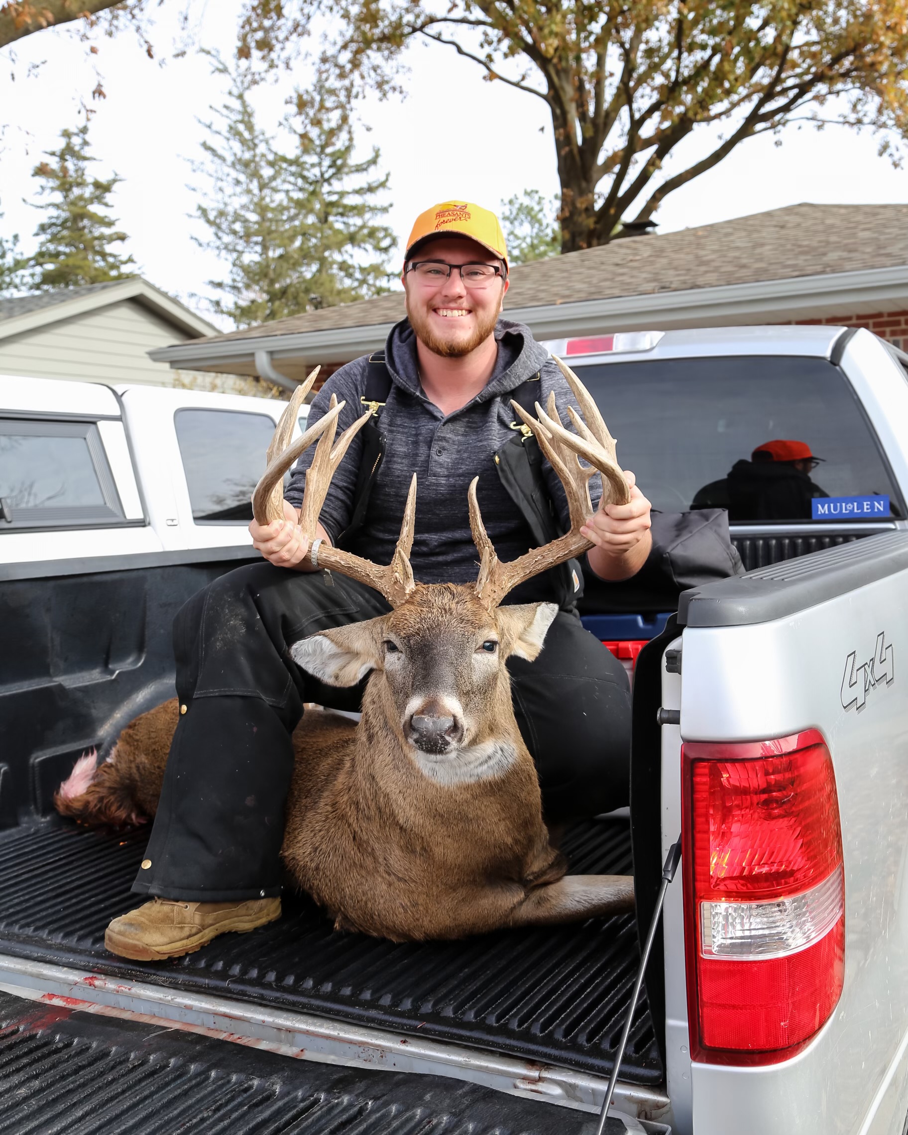 Photo of Regan Archibald in hunting gear with a deer