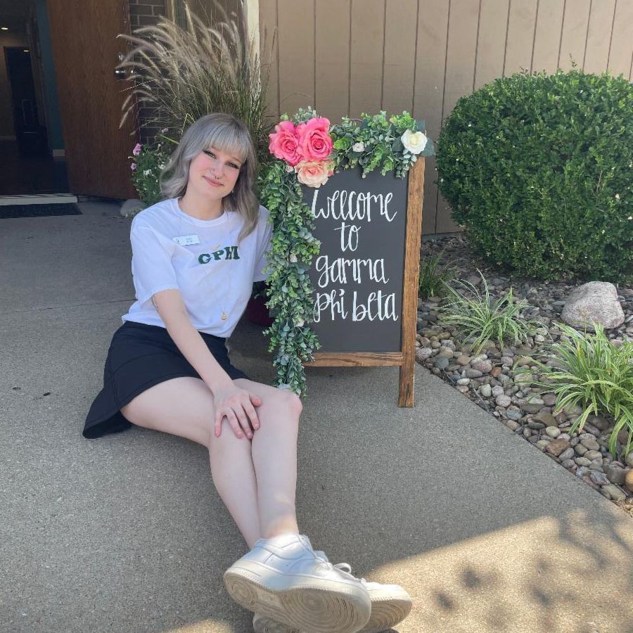 Photo of Emily Evans in front of a Gamma Phi Beta welcome sign