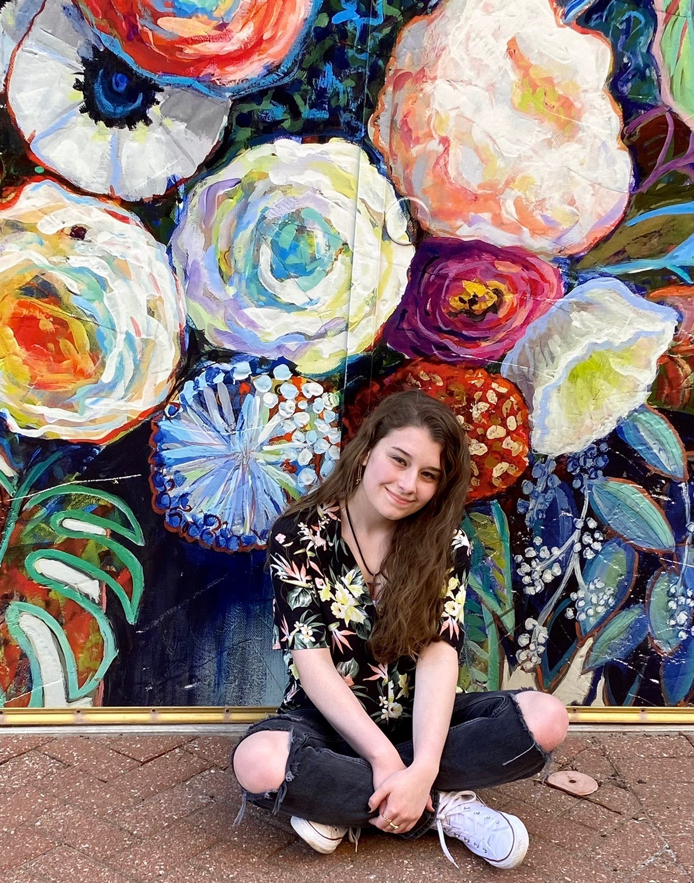 Marcie Schroeder sitting in front of a flower mural