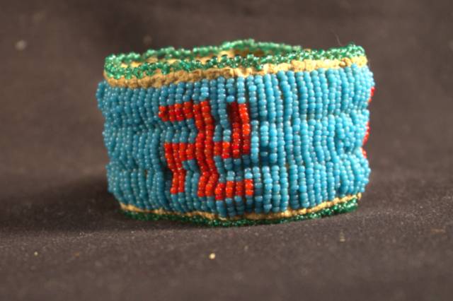 Bracelet A rawhide bracelet that is decorated primarily with blue beads and swastikas made from red beads.