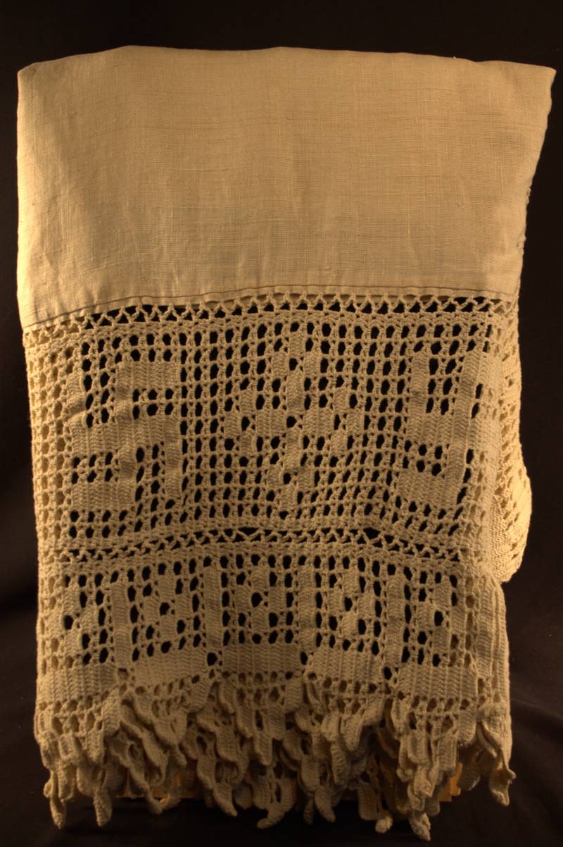 Tablecloth A folded off-white tablecloth showing an alternating patter of swastika symbols and a cross-like symbol.