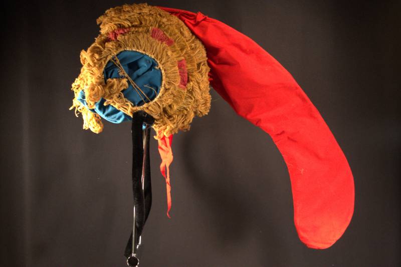 Headdress Headdress is red in color with blue base end and brown with red fur around head part.