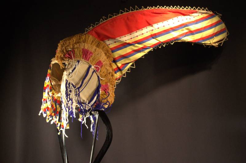 Headdress Headdress is red conical part with blue, red, and yellow stripes with decorative flower patterns.