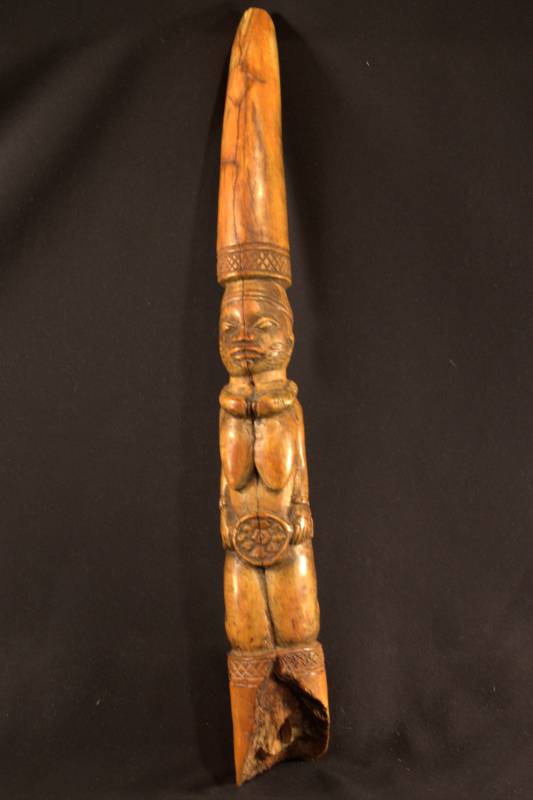 Divination Tapper ange-colored tusk with kneeling female figure wearing a necklace and holding a disk in front.