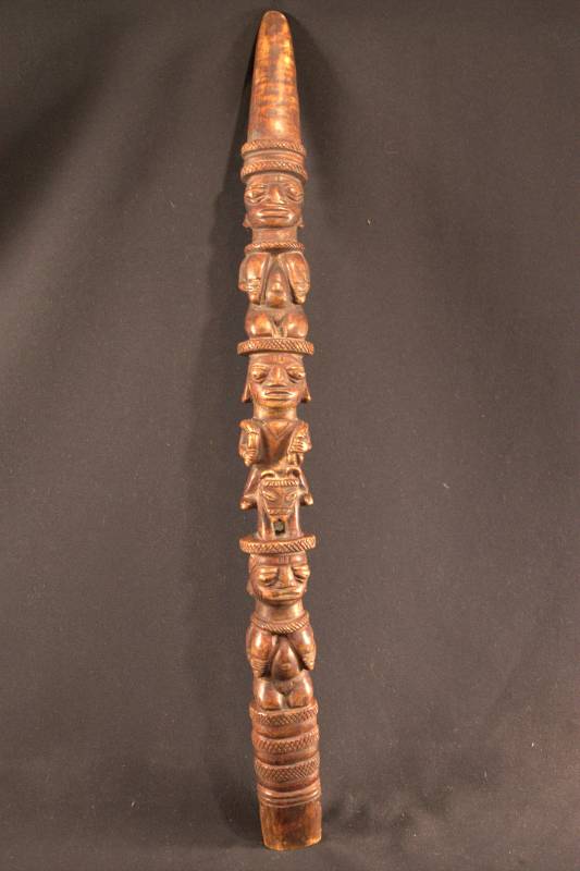 Divination Tapper Curved horn colored dark brown with three figures. On top and bottom are identical kneeling female figures holding their breasts. Middle figure is riding a horse and holding whips or fly whisks in each hand. In-between figures are bands of crisscross patterns.