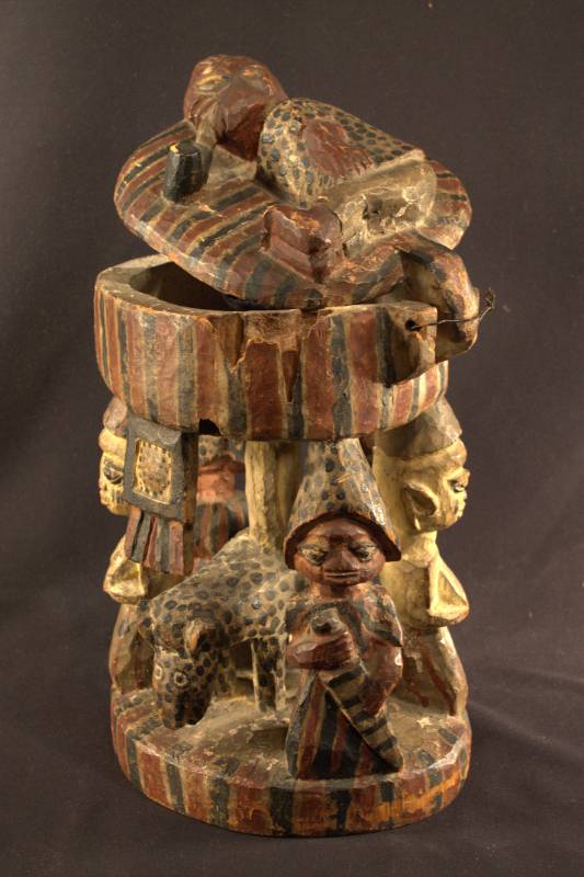 Divination Bowl Divination bowl and lid decorated with red, white, and black stripes. On top of the lid here is a person smoking a pipe. On the base there is a leopard surrounded by three men and a woman.