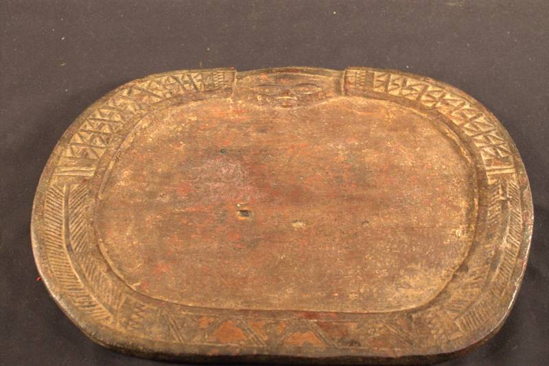Divination Tray Dark brown, wood carved face at the top. Designs all around circumference edge in different patterns, with a crack on one side of the oval-shaped board